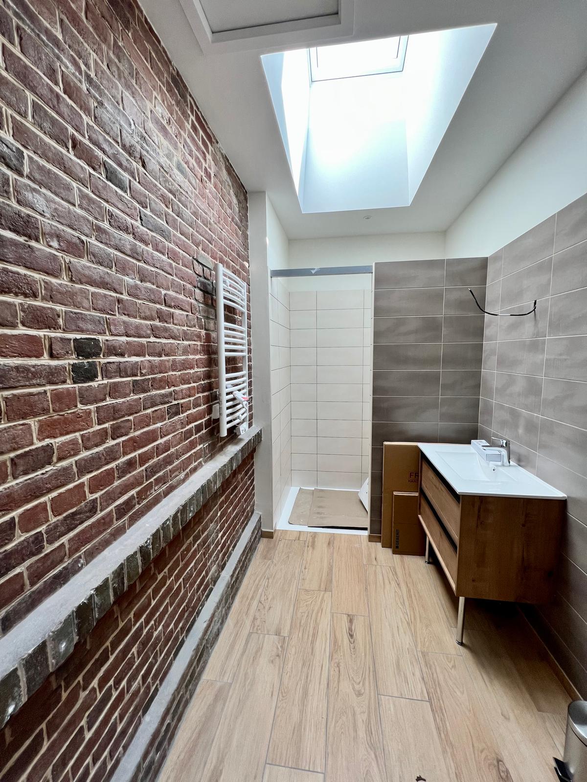 Salle de bain rénovée avec mur de briques et douche, devis rénovation en Normandie